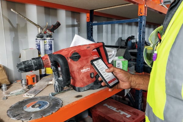 image of a man holding a phone with a red tool in the background