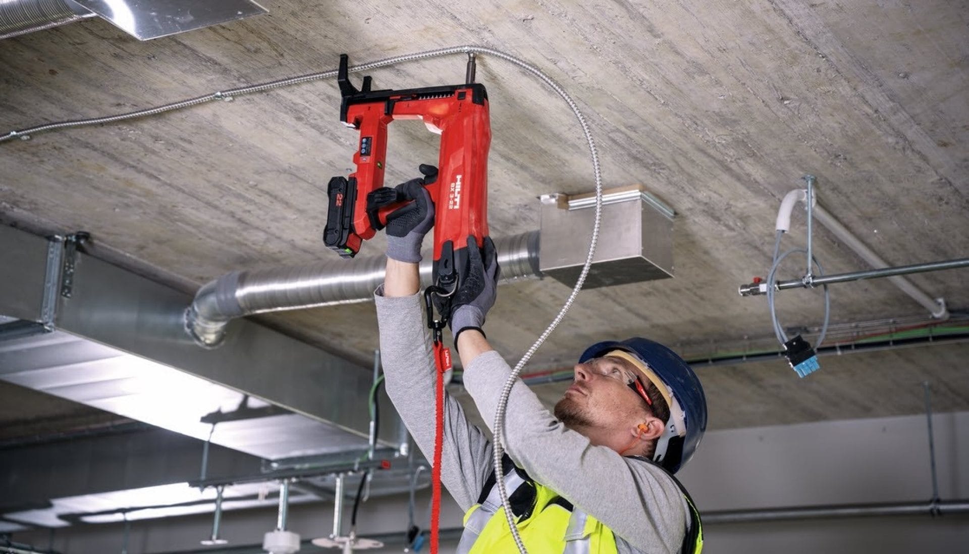 A man in PPE drilling into a roof with a Hilti drill