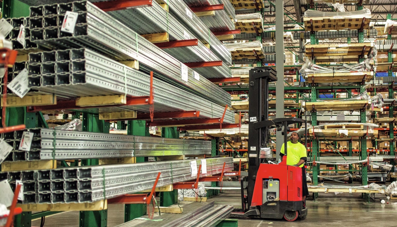 man working in the warehouse in front of a stock of metal bars