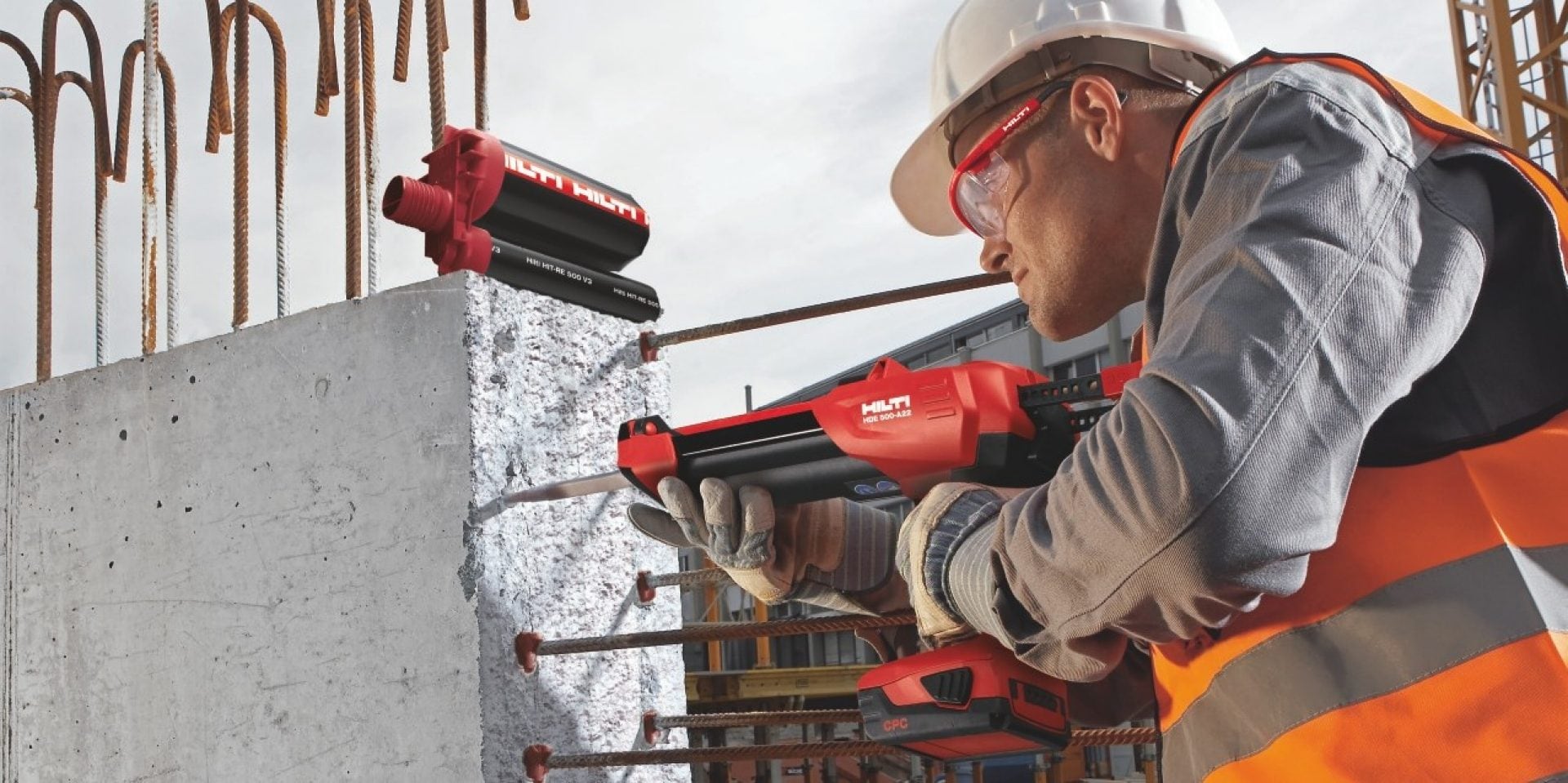 A worker installing a rebar into a concrete wall with a Hilti tool