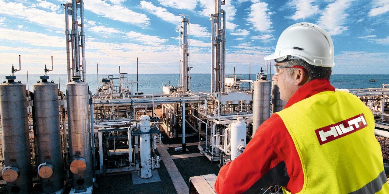 person in a hi vis vest overlooks a power plant