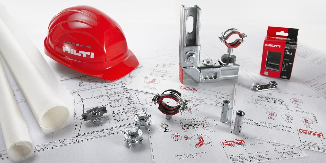 a red helmet lay next to modular components on top of engineering drawings
