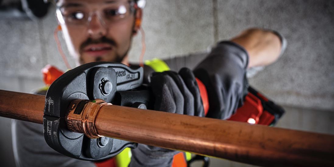 a person using a hilti pipe press tool to fix a copper pipe