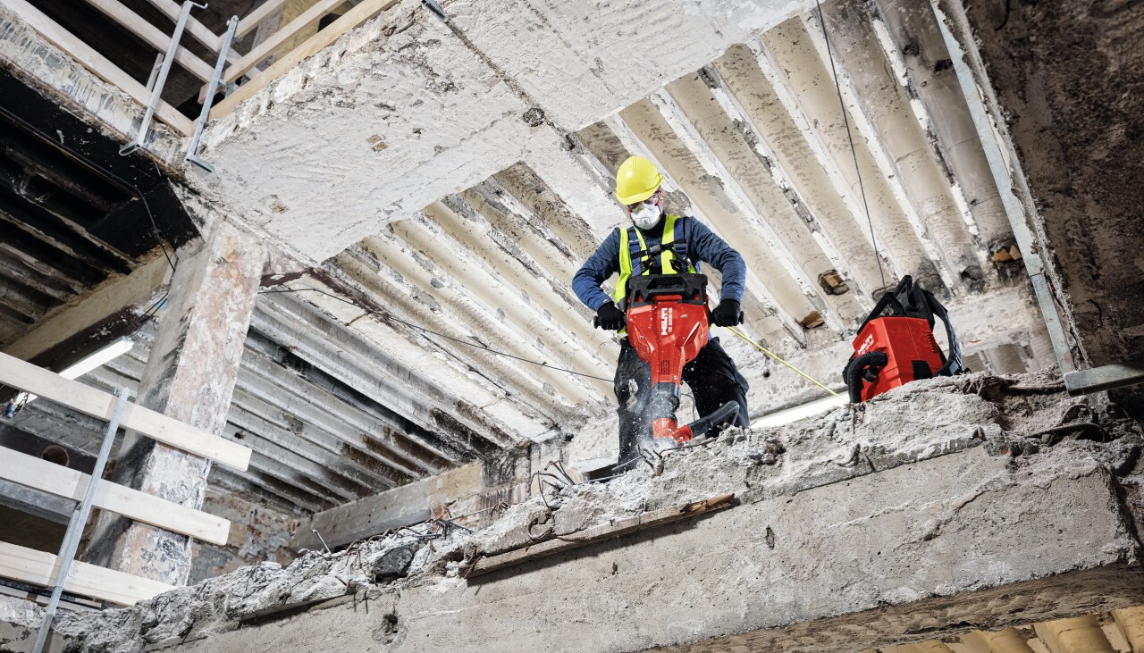 a person using a red hilti breaker to break concrete