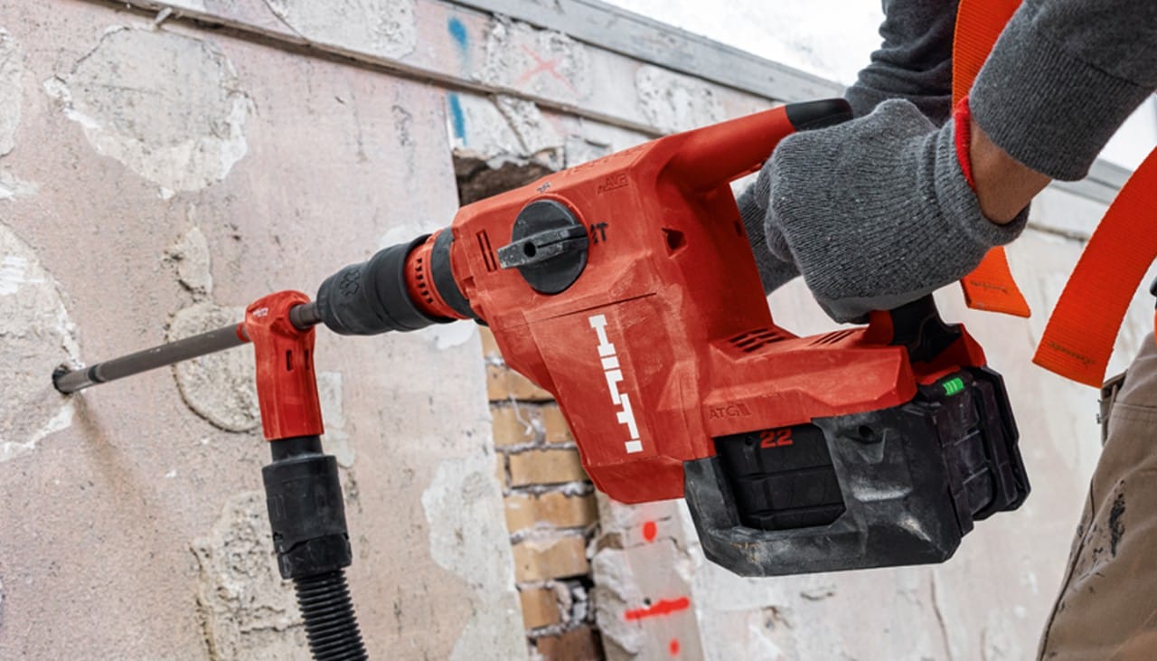 a person using a red hilti drill to drill holes