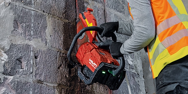 a person using a hilti cut off saw, sawing into a wall