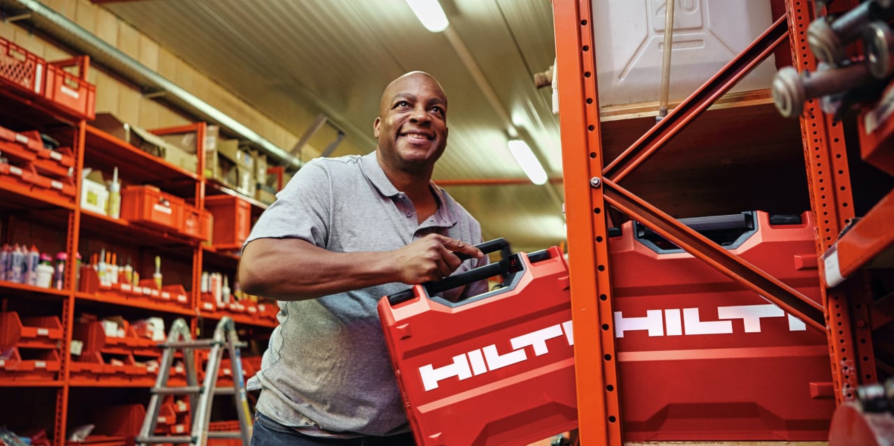 a person taking a red hilti tool case off racking