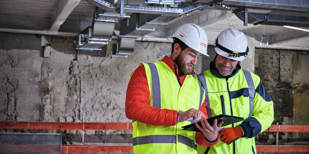 two workmen looking at a tablet screen