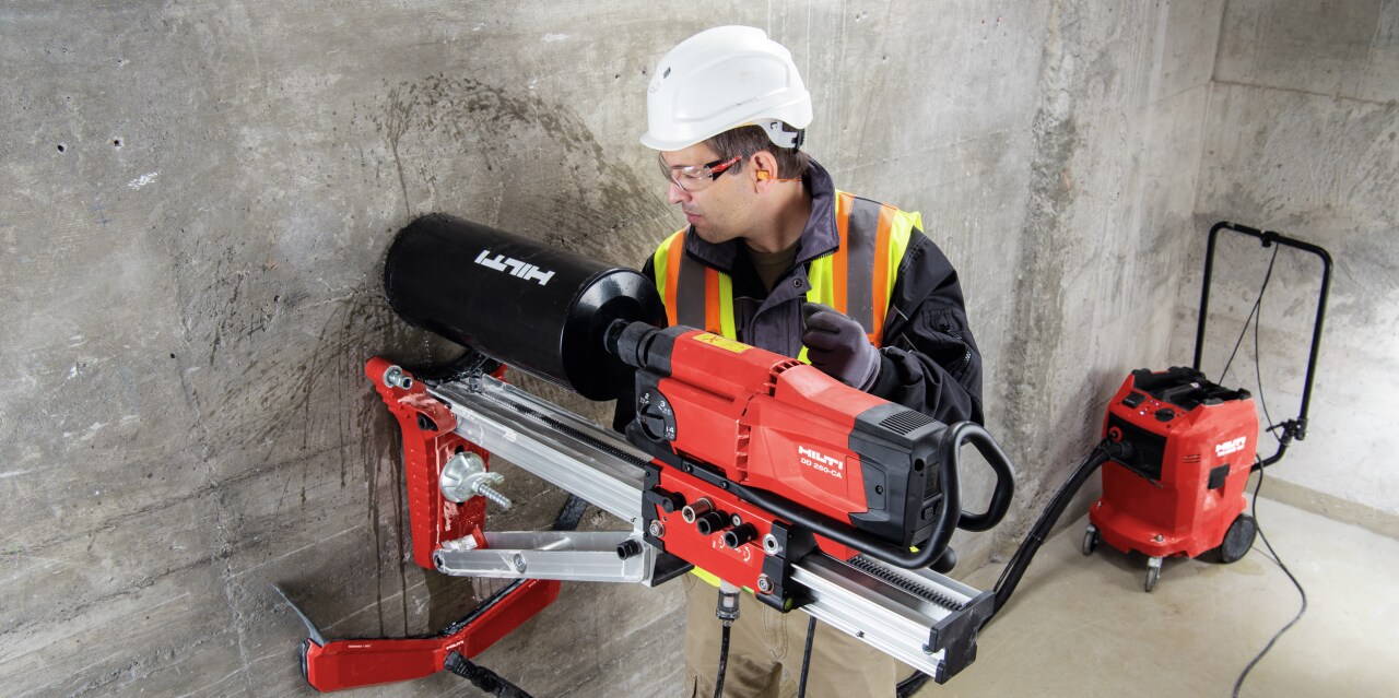 Construction worker using a DD-WMS water management system to supply, filter and collect slurry from wet diamond drilling