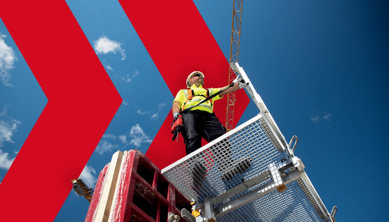 person stood on platform wearing a helmet and hi vis vest