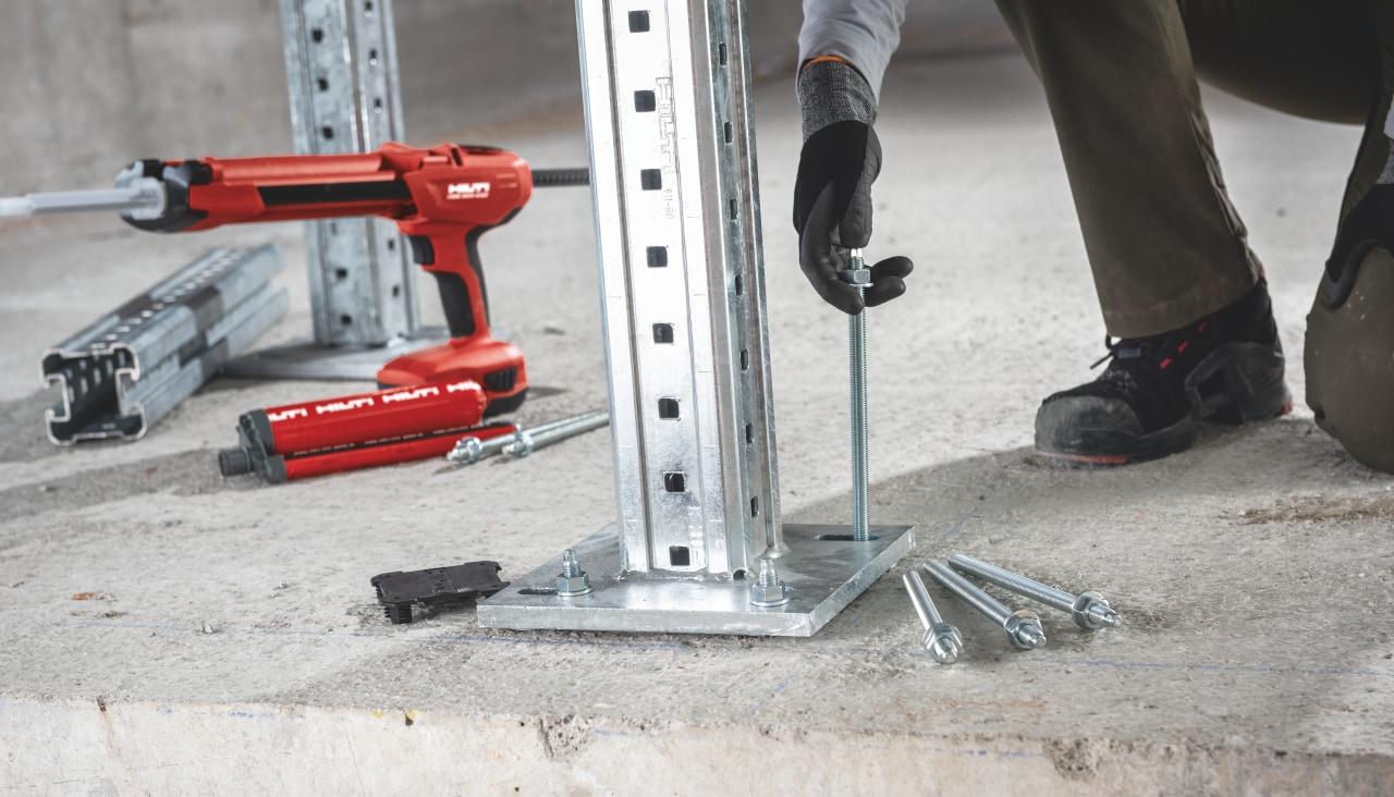 image of a red Hilti resin dispenser sat next to a person installing a base plate using Hilti anchors