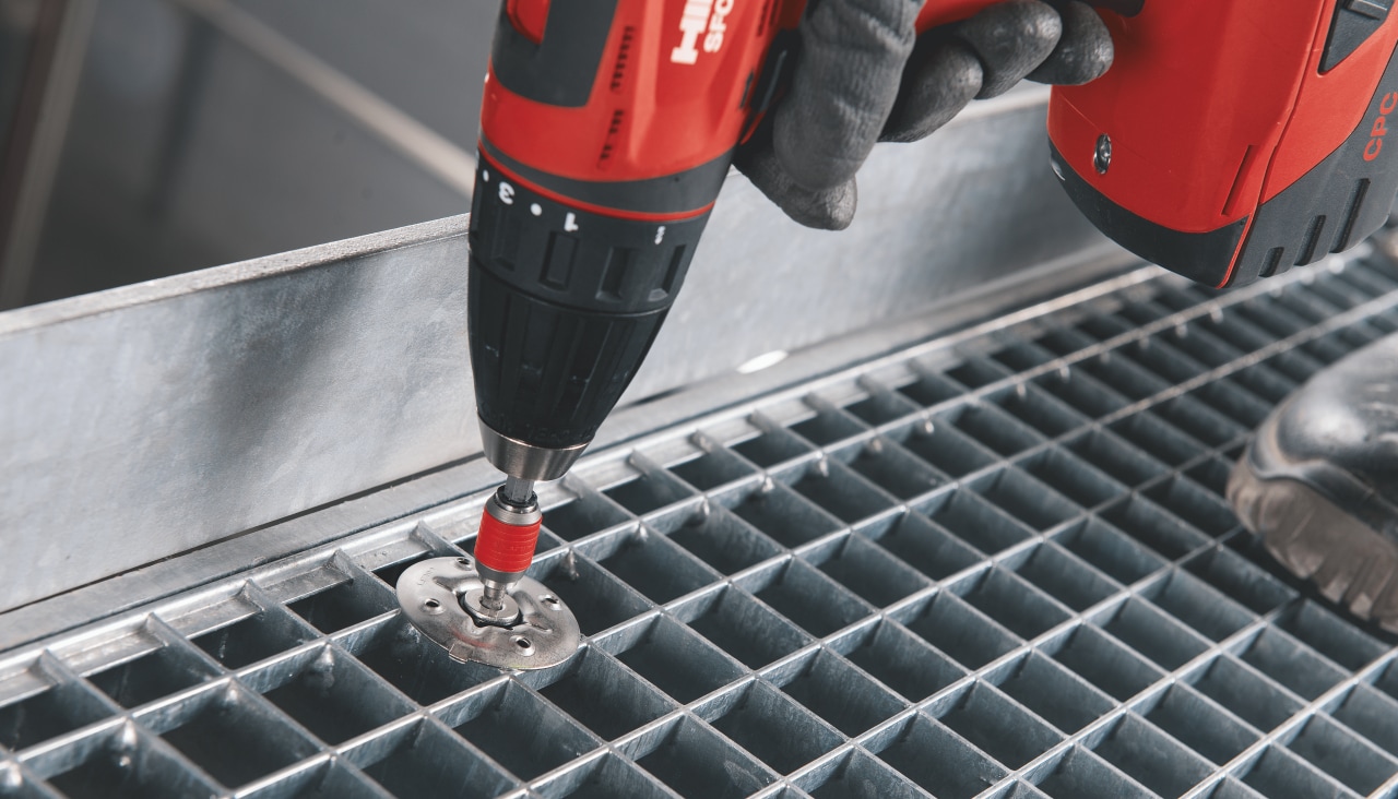 person using a Hilti drill to fix a grating disc to mesh flooring