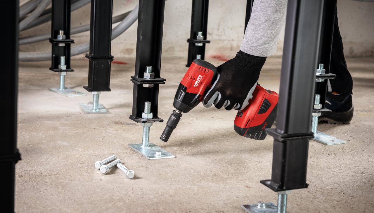 person using a Hilti drill us anchor a base plate into a floor