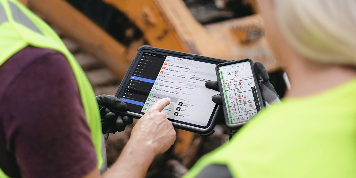 workers showing device screens to each other  on a jobsite