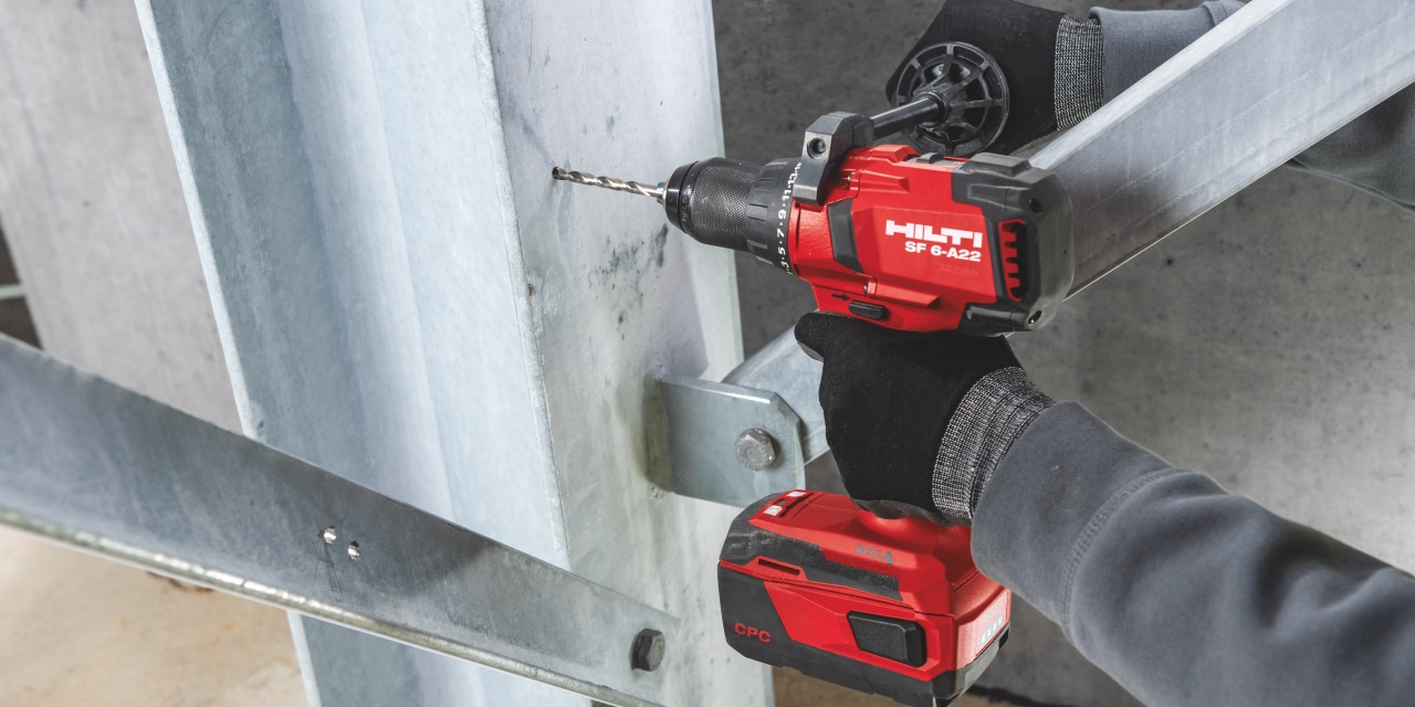 A Hilti drill drilling a hole into a steel girder