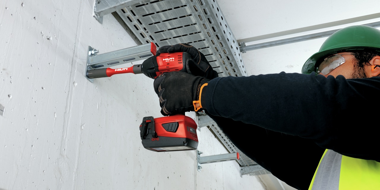 A worker drilling a hole into a wall with a Hilti drill