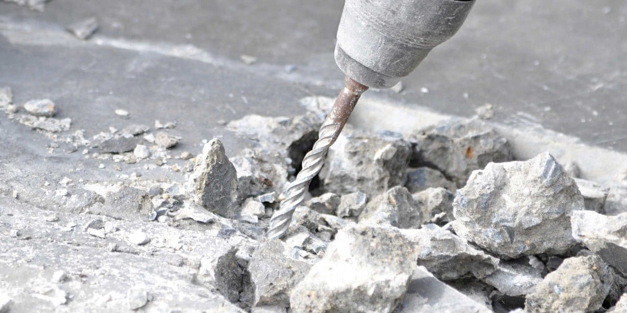 a drill drilling into concrete producing dust