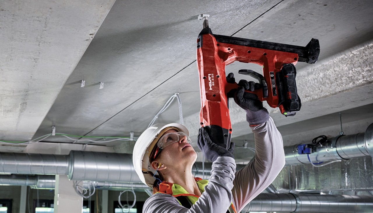 person using a hilti red tool against a ceiling to insert a fastener