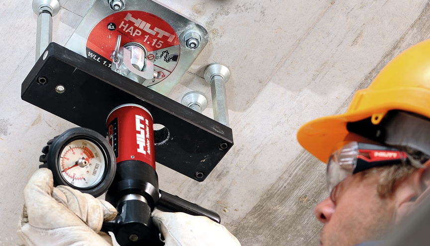 person using a anchor load tester up against a ceiling